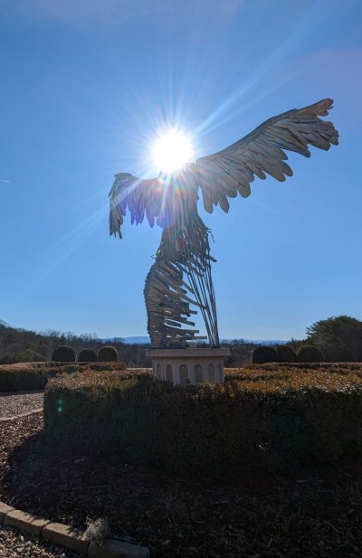 A metal sculpture with the sun shining above it