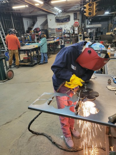 A person cutting a metal flower from a sheet of metal